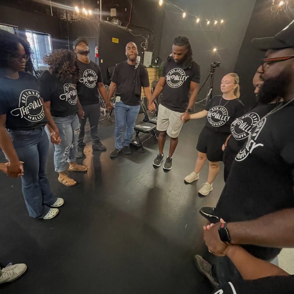 Church members standing in a circle, holding hands in prayer